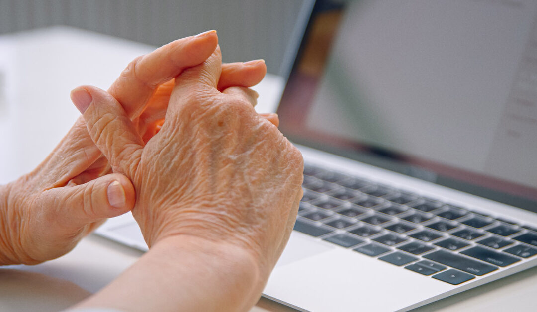 a female manager holds her wrinkled, aging hands over her laptop keyboard